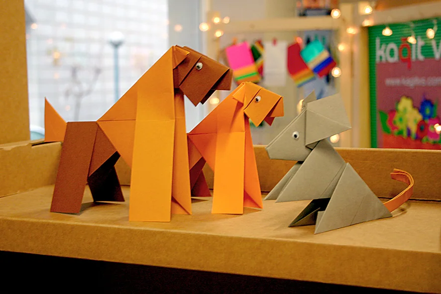 Orange, brown, and grey origami dogs displayed inside a Kağıt vs. shop.